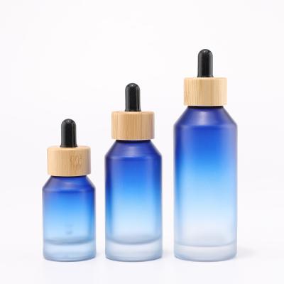 botella de vidrio azul degradado con cuentagotas de bambú para envases cosméticos
