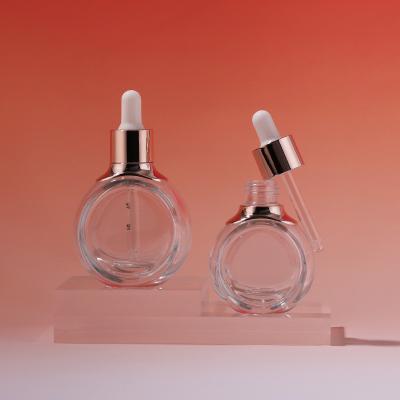 Botella cosmética con cuentagotas de vidrio de forma circular plana transparente
        