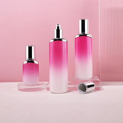 Frasco y botella de vidrio cosmético de color rosa degradado de lujo con tapa plateada de bomba